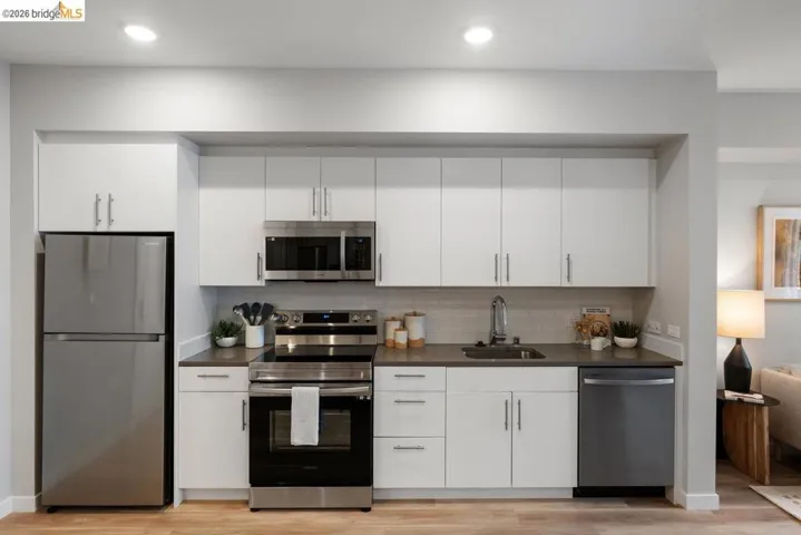 Kitchen with appliances with stainless steel finishes, white cabinets, backsplash, light wood-style flooring, and recessed lighting