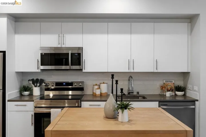 Kitchen with stainless steel appliances, white cabinets, tasteful backsplash, and wooden counters