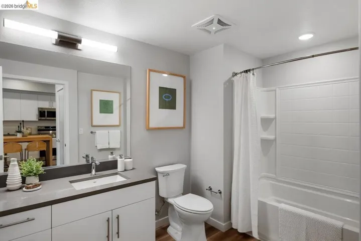 Bathroom with vanity, dark wood finished floors, and shower / bath combination with curtain