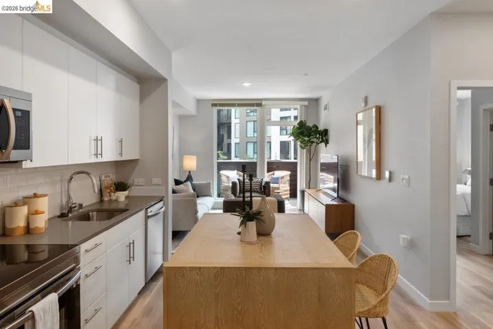 Kitchen with light wood finished floors, open floor plan, stainless steel appliances, white cabinetry, and recessed lighting