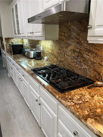 View of Kitchen Granite Countertop and 5 Burner Cooktop Range.