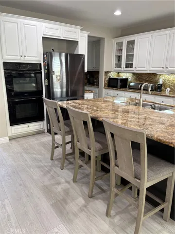 Kitchen Island with Granite Top with seating for three and view of Double Over next Stainless Steel Fridge.