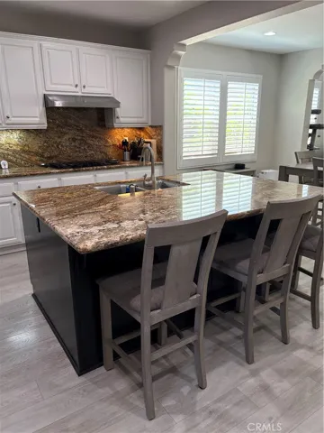 Kitchen Island, Stainless Sink and view of Casual Dining Table for four on the right side of the Kitchen.
