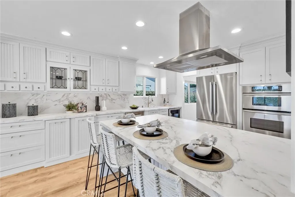 Remodeled kitchen features matte finish porcelain counters and brass and acrylic cabinet hardware.