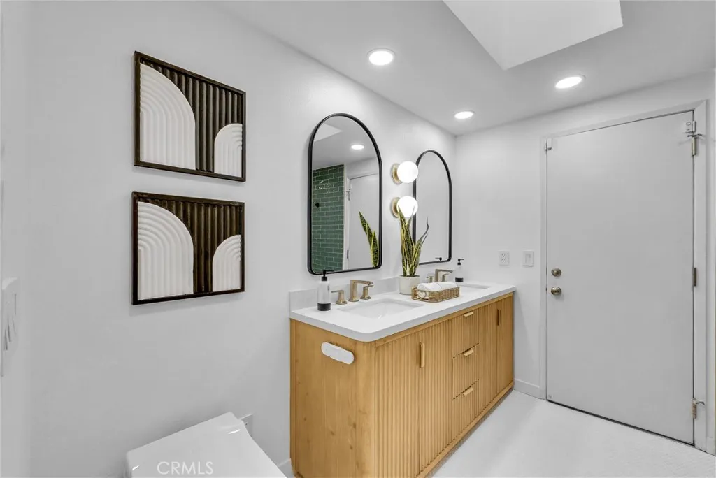 Remodeled hall bathroom with modern dual vanity, curb-less, walk-in shower along with a smart toilet and penny tile floors. There is also a door leading to the pool/spa area for added convenience.