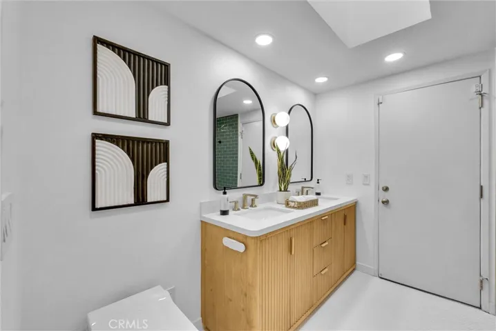 Remodeled hall bathroom with modern dual vanity, curb-less, walk-in shower along with a smart toilet and penny tile floors. There is also a door leading to the pool/spa area for added convenience.