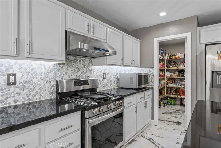 Modern kitchen equipped with dark countertops and white cabinetry.