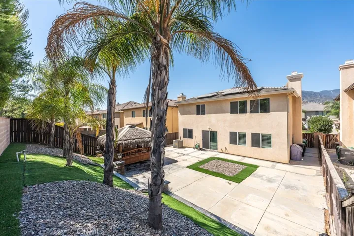 Exterior view of the home featuring a spacious driveway and tropical landscaping.