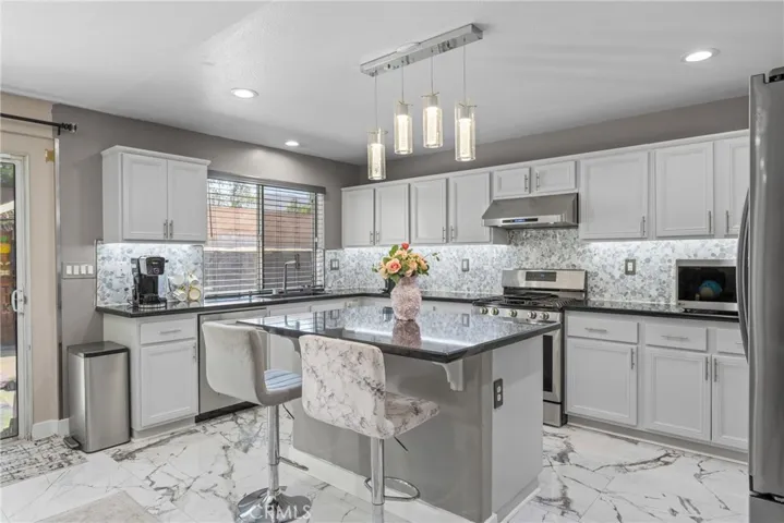 Stunning modern kitchen equipped with stainless steel appliances, white cabinetry, and a large center island.