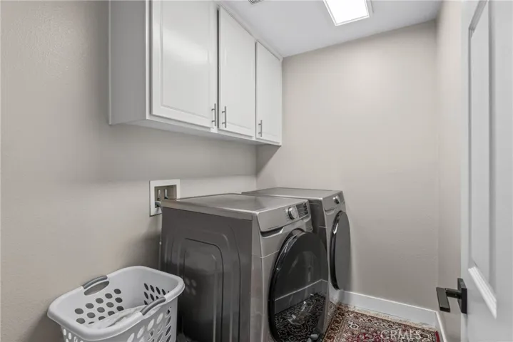 Convenient indoor laundry room with upper storage cabinets.
