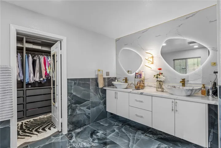 Luxurious bathroom featuring a dual sink vanity, stylish lighting, and a glass-enclosed walk-in shower.