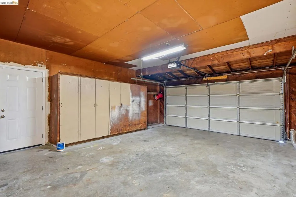 Spacious garage featuring a concrete floor, built-in storage cabinetry, overhead lighting, and an automatic garage door opener