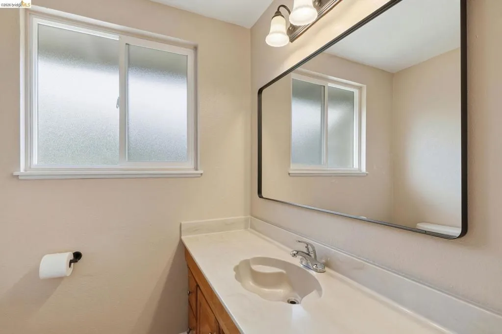 Bathroom vanity featuring an integrated sink, polished chrome faucet, and expansive wall-mounted mirror