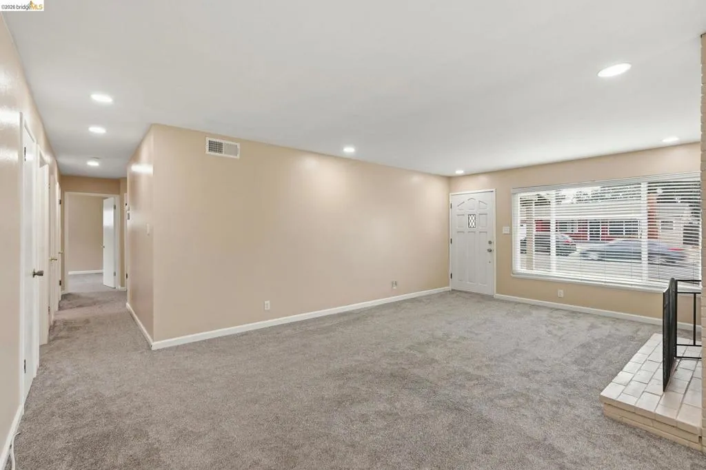 Spacious living area featuring neutral-toned walls, recessed lighting, and soft gray carpeting throughout