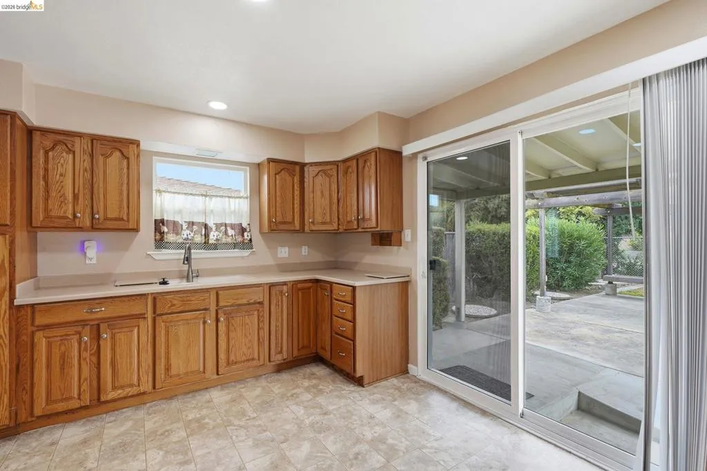 Kitchen area featuring wood cabinetry, a window over the sink, and recessed lighting