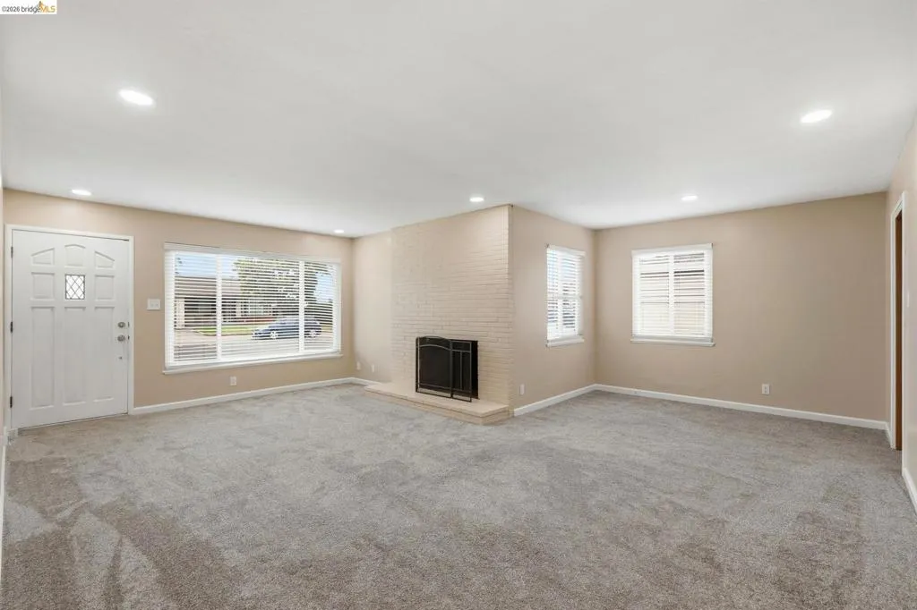 Spacious living area featuring neutral-toned walls, recessed lighting, and grey carpeting