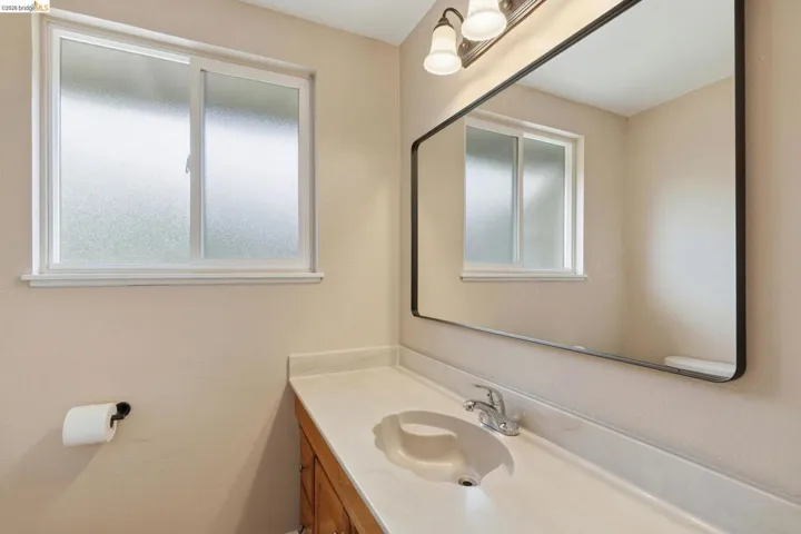 Bathroom vanity featuring an integrated sink, polished chrome faucet, and expansive wall-mounted mirror