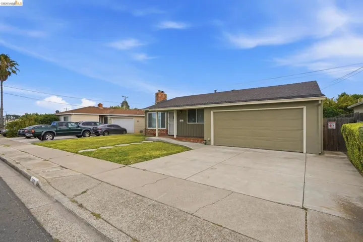 Ranch-style residence featuring an attached garage, concrete driveway, and established front lawn