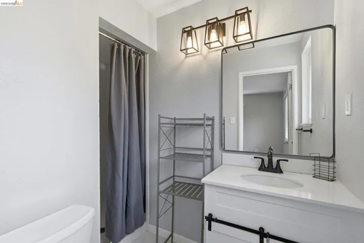 Bathroom featuring a white vanity with a white countertop, an undermount sink, and a matte black faucet