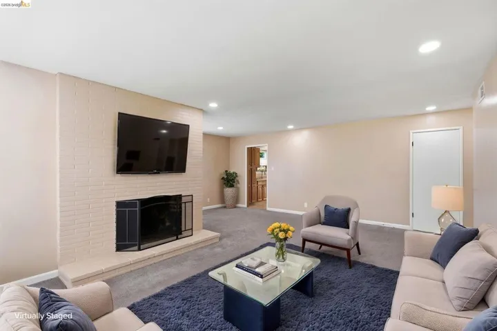 Living area featuring a painted brick fireplace with a hearth, recessed lighting, and carpet flooring