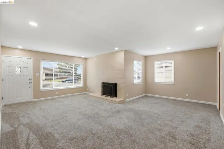 Spacious living area featuring neutral-toned walls, recessed lighting, and grey carpeting