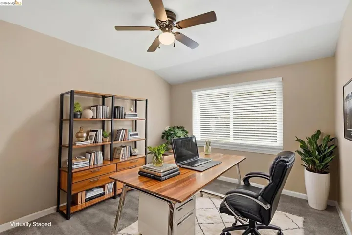 Spacious room featuring vaulted ceilings, a ceiling fan with integrated lighting, and neutral wall tones