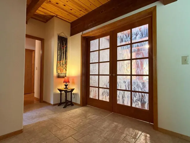 Entry features custom French doors with iridescent stained glass leading to living room