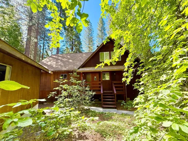 The view of the front of the house as seen through the dogwood grove. 2-car garage is to the left