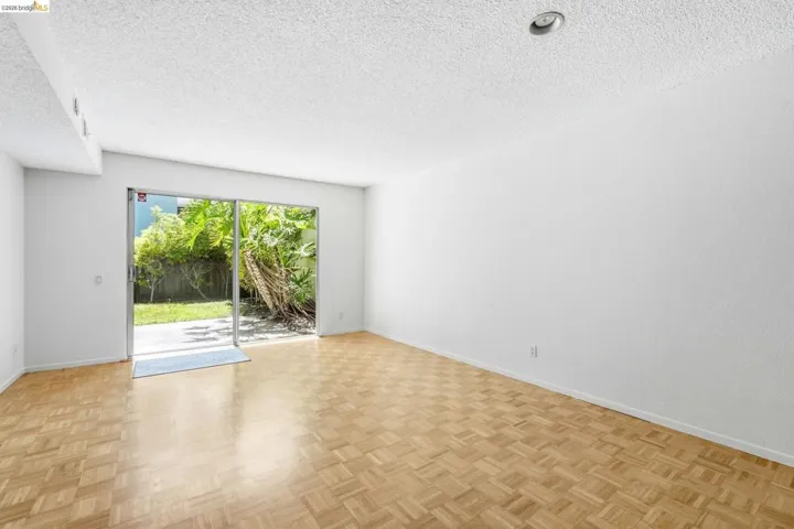 Spacious room featuring wood-finish parquet flooring and white walls