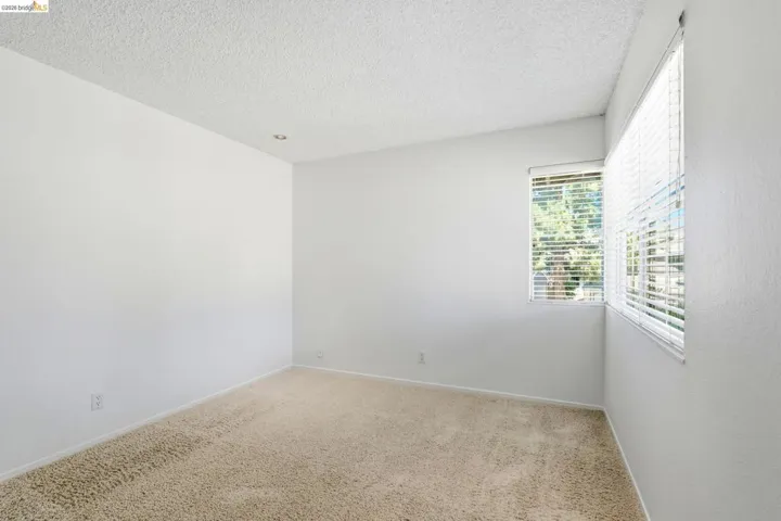 Carpeted room with white walls, two windows with blinds, and recessed lighting
