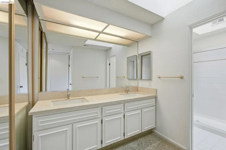Bathroom featuring a double vanity with integrated sinks, stone-finish countertop, and white cabinetry