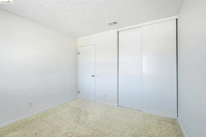 Room featuring light-colored carpeting, white walls, and a textured ceiling