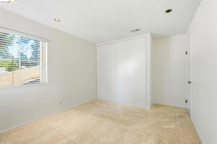 Light beige carpeted room with a window featuring horizontal blinds