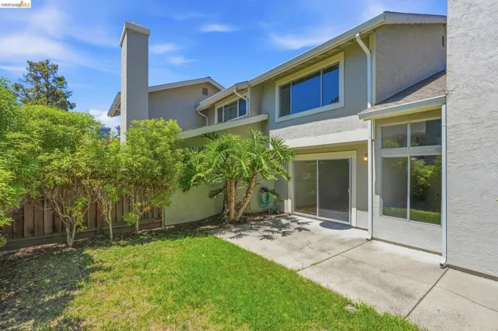 Private patio with concrete surfacing, sliding glass door access, and a manicured lawn area