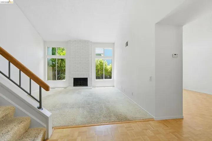 Living area featuring a brick fireplace, large windows, light-toned carpeting, and parquet wood flooring