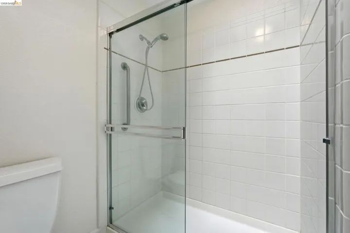 Shower enclosure with clear glass sliding doors and integrated grab bar