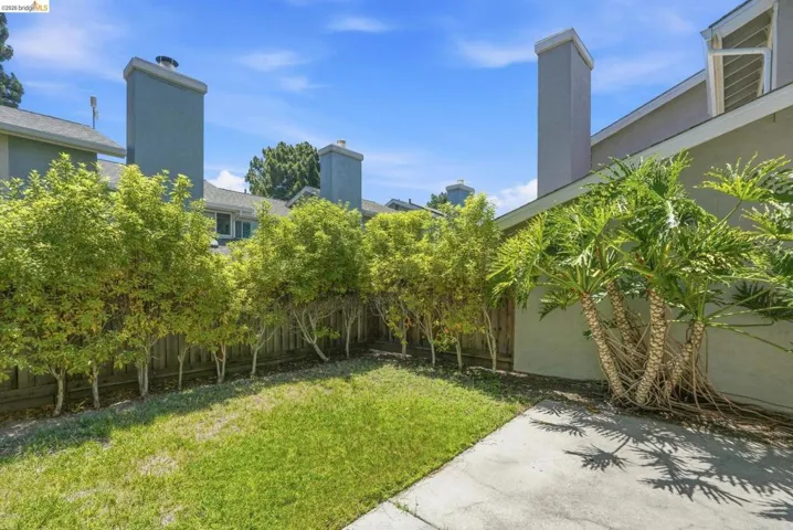 Private backyard space featuring a concrete patio, a section of turf, and a wood fence