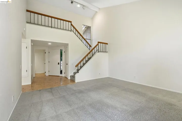 Spacious living area featuring a two-story ceiling and a carpeted floor