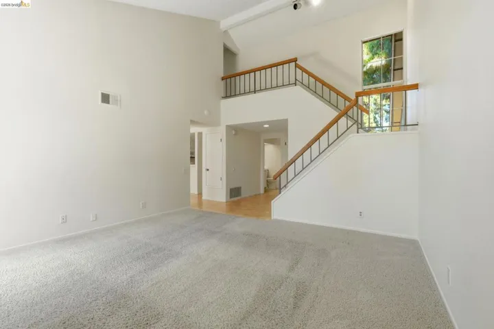 Vaulted ceiling living space with light gray carpeting and white painted walls