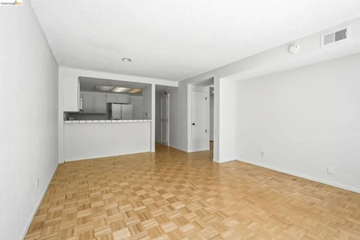 Parquet wood-finish flooring extending into a spacious living area featuring a kitchen pass-through with white tiled countertop
