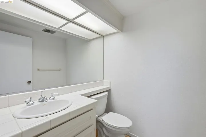 Bathroom featuring a spacious vanity with tiled countertop, integrated sink, and chrome faucet