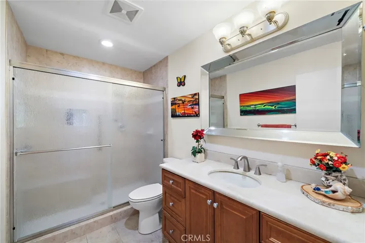 downstairs remodeled bathroom with a natural stone vanity and walk-in shower