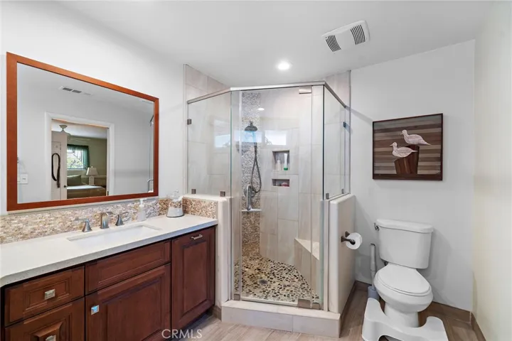 a walk-in shower with stone flooring, bench, and niche