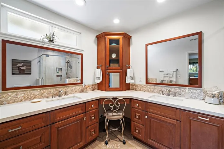 expanded ensuite with dual quartz vanities, a sit-down makeup station with hidden outlets