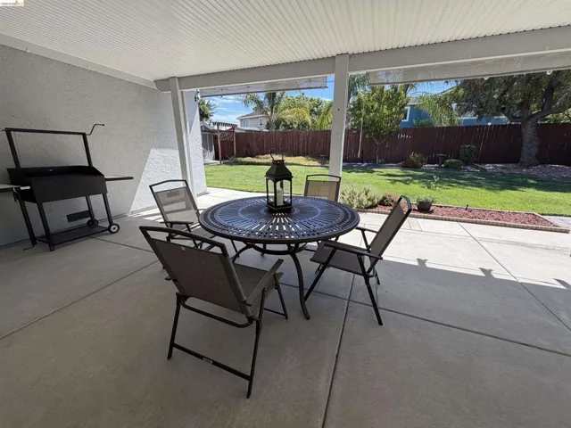 Spacious covered patio area with concrete flooring, offering direct access to a manicured lawn