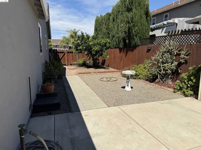 Rear yard featuring a concrete patio, gravel landscaping, and a wood fence