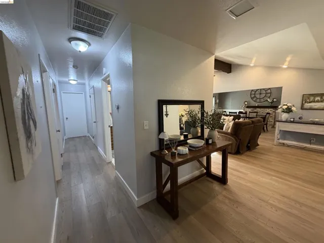 Open-concept living space with light wood-finish flooring and a hallway featuring neutral wall tones