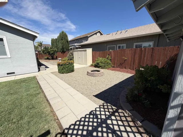 Expansive rear yard featuring a gravel patio, built-in fire pit, storage shed, and perimeter fencing