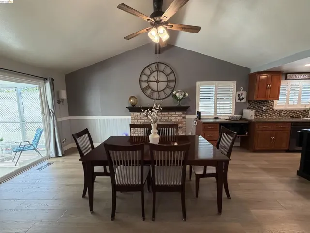 Dining area featuring vaulted ceilings with a ceiling fan, light wood-finish flooring, and a brick fireplace