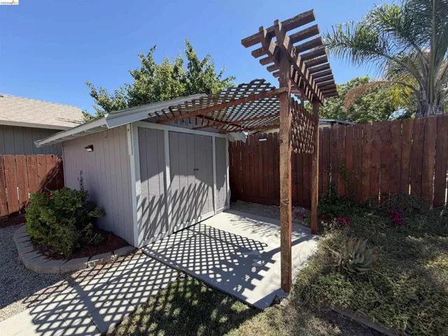 Freestanding shed with light grey siding and a coordinating pergola structure